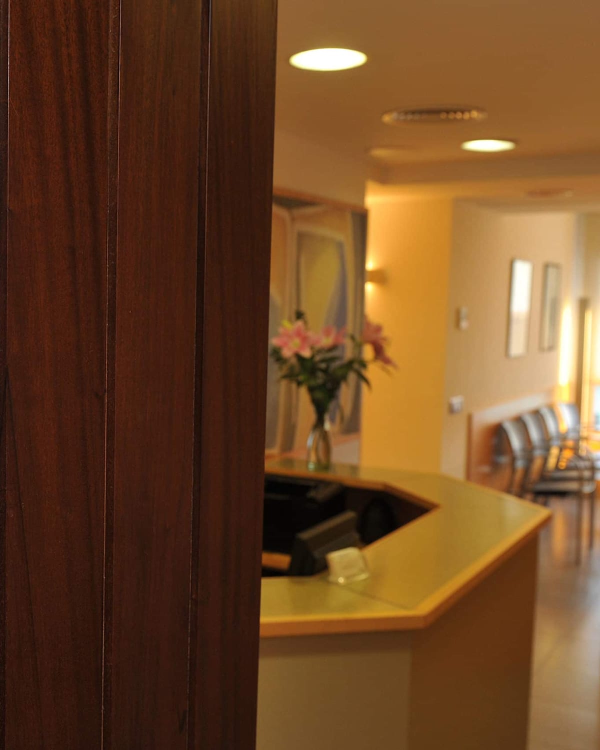 La porta de la clínica oberta, amb la recepció i la sala d'espera al fons